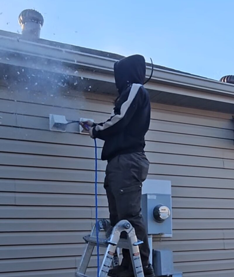 Air-Vac Services technician cleaning an exterior dryer vent in the Fargo-Moorhead area